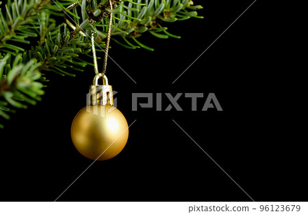 Yellow ball on a green branch of a Christmas tree isolated on a black background. Holiday concept Yellow ball on a green branch of a Christmas tree isolated on a black background. Holiday concept 96123679