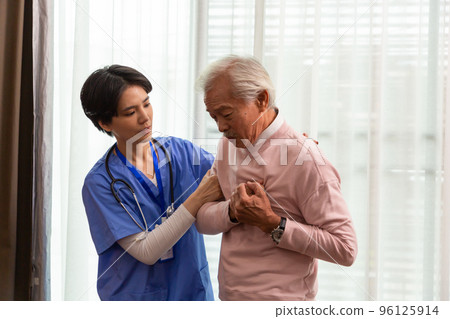 Friendly staff care giving Senior man suffering from heart attack at home. Man clutching his chest. Pain, possible heart attack 96125914