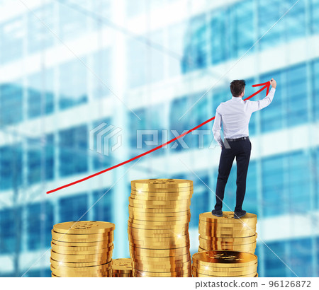 Businessman draws growing arrow of company statistics over a pile of money Businessman draws growing arrow of company statistics over a pile of money 96126872