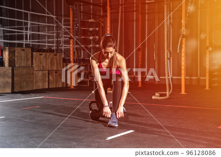 Athletic girl ready to start exercises with a kettlebell at the gym 96128086