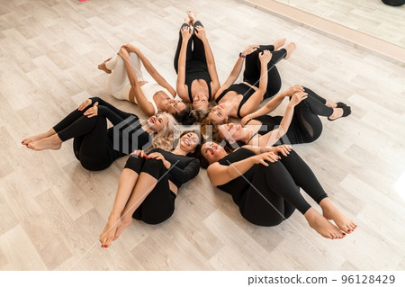 Seven happy women lie on their backs on the floor with their heads pressed together. Seven happy women lie on their backs on the floor with their heads pressed together. 96128429