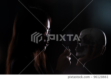 Detective Collecting looking Evidence cause of dead in a Crime Scene. White Bone Skull found under Sand. Magnifier investigate some clue mystery, copy space. Dark silhouette 96128661