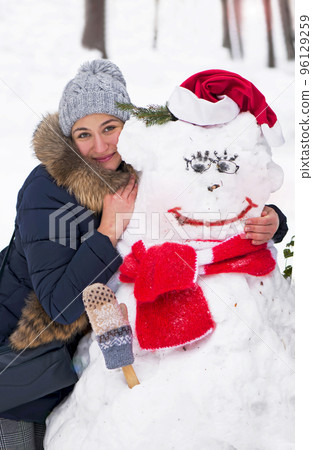 girl hugging a snowman. winter theme - girl hugging a snowman outdoors girl hugging a snowman. winter theme - girl hugging a snowman outdoors 96129259