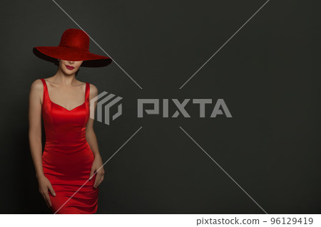 Sensual beautiful woman brunette posing in red dress and red wide broad brim hat Sensual beautiful woman brunette posing in red dress and red wide broad brim hat 96129419