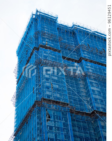 Building under construction wrapped blue protection safety net Building under construction wrapped blue protection safety net 96129451