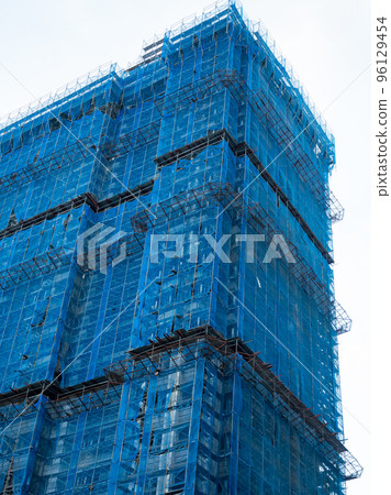 Building under construction wrapped blue protection safety net Building under construction wrapped blue protection safety net 96129454