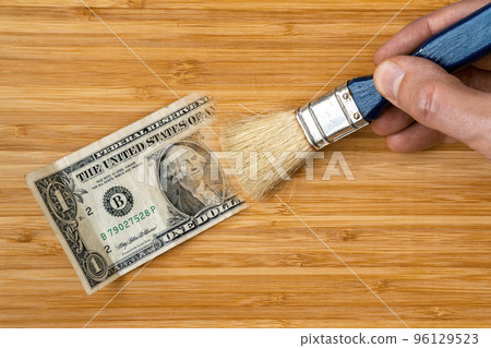 Hand with a brush painting one dollar bill on the wooden background 96129523
