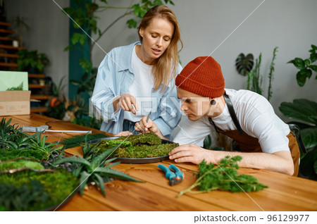 Woman florist teaching young hipster man decorator at art craft studio 96129977