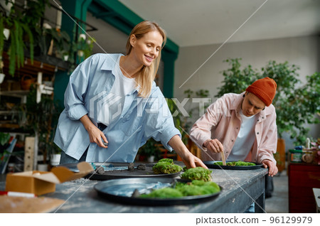 Young family couple of floral designer composing fresh cut green platter 96129979