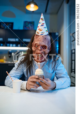 Happy creepy zombie employee with birthday cake portrait Happy creepy zombie employee with birthday cake portrait 96130152