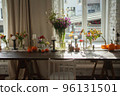 Variety of flowers in a vase on a wooden table in a vintage style room 96131501