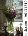 Variety of flowers in a vase on a wooden table in a vintage style room 96131510