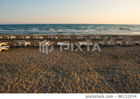White sunbeds in a sandy beach at sunset 96132034