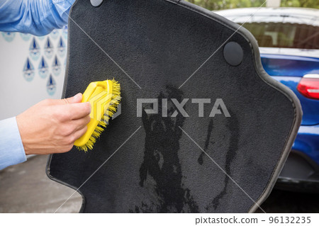The hand of the person cleans an automobile rug 96132235
