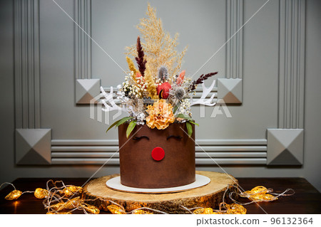 Christmas Banana Cake with Vanilla cakes, Cream Cheese and Salted Caramel on the background of candles, garlands, fir branches and cones 96132364