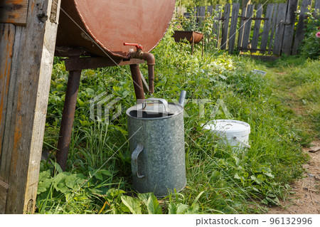 Rain barrel and watering can in vegetable garden. Watering the garden during a drought. Rain barrel and watering can in vegetable garden. Watering the garden during a drought. 96132996