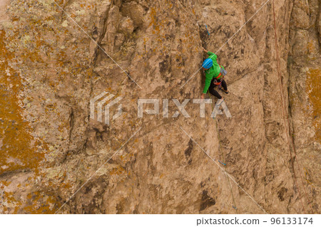 Man Climber Rock Climbing. Cliffs in Tamgaly Tas, Kazakhstan. Aerial View Man Climber Rock Climbing. Cliffs in Tamgaly Tas, Kazakhstan. Aerial View 96133174