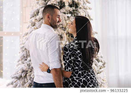 Back view of man an woman decorate Christmas tree at home. Fairytale Back view of man an woman decorate Christmas tree at home. Fairytale 96133225