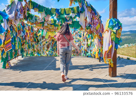 A girl walks under an arch with traditional Buddhist prayer flags in the Rinpoche Bagsha datsan in Ulan-Ude city of the Republic of Buryatia, Russia. A girl walks under an arch with traditional Buddhist prayer flags in the Rinpoche Bagsha datsan in Ulan-Ude city of the Republic of Buryatia, Russia. 96133576