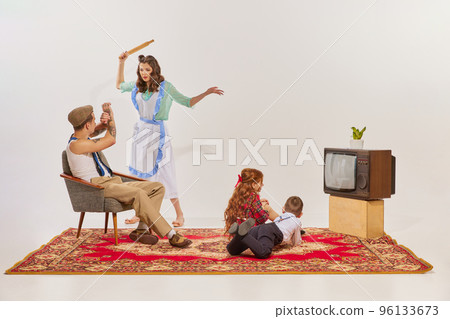 Portrait of young family watching TV isolated over grey background. Kids watching cartoons, man and woman quarreling 96133673