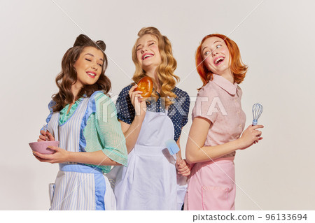 Portrait of beautiful, cheerful young women, housewives with cooking tools isolated over grey background. Pop art 96133694
