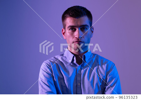 A man in a shirt poses on a dark multicolored neon background 96135323
