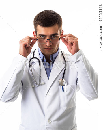 Confident male doctor in white lab coat and stethoscope standing with folded arms smiling at the camera isolated on white Confident male doctor in white lab coat and stethoscope standing with folded arms smiling at the camera isolated on white 96135348