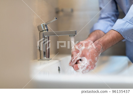 Man using soap and washing hands under the water tap. Hygiene concept hand closeup detail. Man using soap and washing hands under the water tap. Hygiene concept hand closeup detail. 96135437