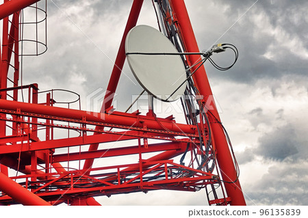 Part of communication tower with satellite dish against backdrop of dramatic sky with storm clouds. Telecommunication tower close-up. 96135839