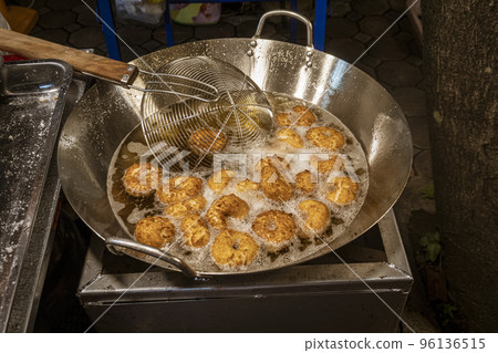 Tiny donuts being cooked at outdoor night street market 96136515