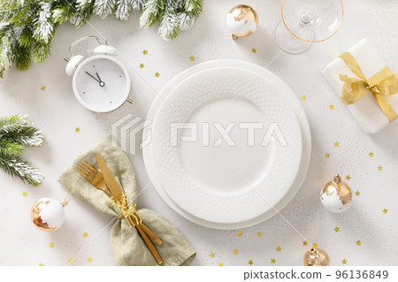 Beautiful Christmas festive table setting with white plate, golden balls on white. 96136849
