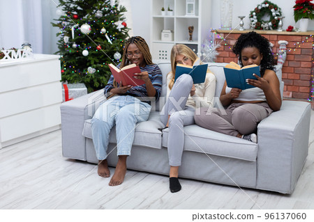 Girls focused while reading a book on Christmas Day. 96137060