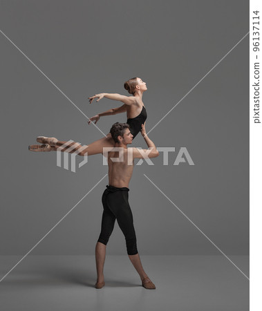 Young man and woman, ballet dancers performing isolated over dark grey studio background. Flying on a shoulder Young man and woman, ballet dancers performing isolated over dark grey studio background. Flying on a shoulder 96137114