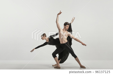 Young man and woman, ballet dancers performing isolated over grey studio background. Flexibility and tenderness Young man and woman, ballet dancers performing isolated over grey studio background. Flexibility and tenderness 96137125