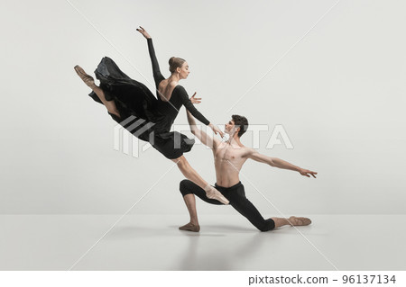 Young man and woman, ballet dancers performing isolated over grey studio background. Twine jump 96137134
