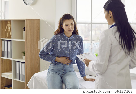 Female patient with abdominal pain undergoing medical examination by doctor for indigestion. 96137165