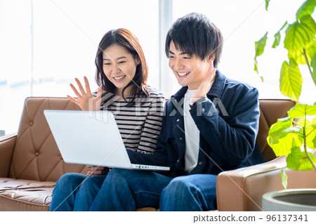 一對夫婦 2 微笑的男女坐在客廳的沙發上視頻聊天 一對夫婦 2 微笑的男女坐在客廳的沙發上視頻聊天 96137341