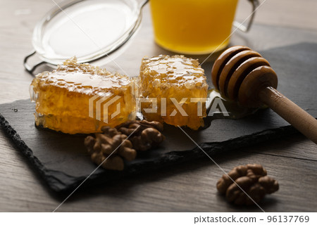 Honeycomb on slate tray with honey and nuts on kitchen table 96137769