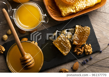 Honeycomb on slate tray with honey and nuts on kitchen table 96137770