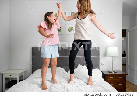 Family fun. Mother and daughter jumping on the bed 96138458