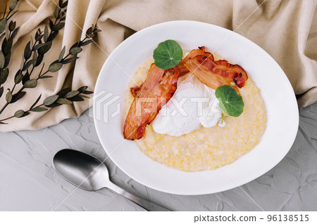 Savory oatmeal porridge with poached egg and bacon 96138515