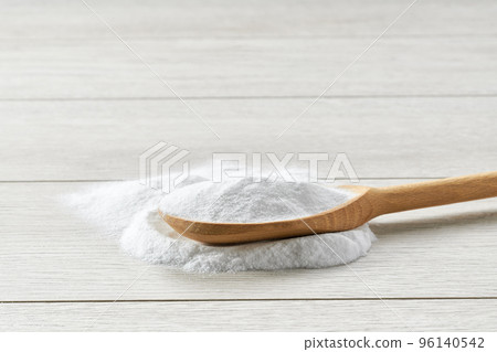 Sodium bicarbonate in a wooden spoon on a light wooden table. 96140542