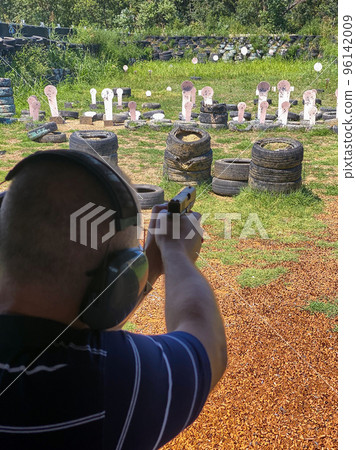 Man firing pistol at target in outdoor shooting range 96142009