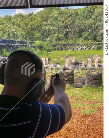 Man firing pistol at target in outdoor shooting range 96142017