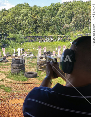 Man firing pistol at target in outdoor shooting range 96142021