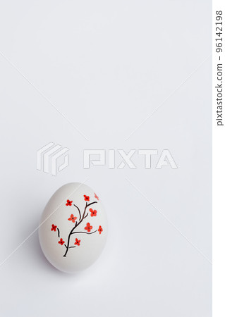 Happy Easter. White egg is beautiful, on which is a beautifully painted tree with red flowers on white background. Stylish gentle spring template with place for Copy text. Vertical photo Happy Easter. White egg is beautiful, on which is a beautifully painted tree with red flowers on white background. Stylish gentle spring template with place for Copy text. Vertical photo 96142198
