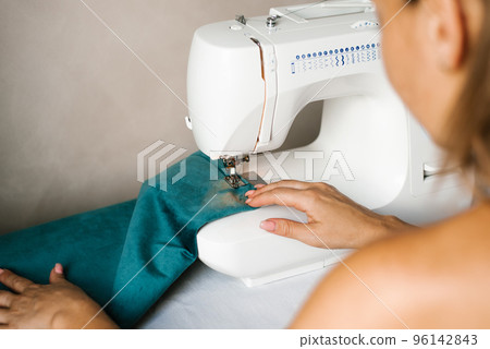 Hands in the process of sewing. Women's hands sew fabric on a hobby typewriter at home. Hands in the process of sewing. Women's hands sew fabric on a hobby typewriter at home. 96142843