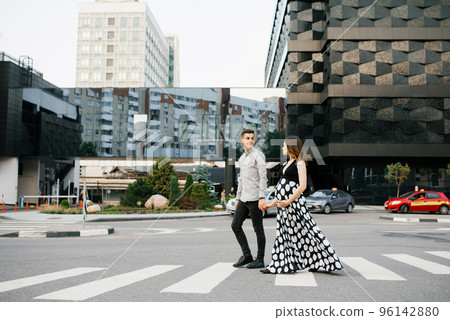 a young family is waiting for the baby. Husband and wife look at each other as they walk through downtown. 96142880