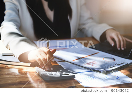 economists and accountants , data analysts are using calculators to calculate budgets and investments using statistical documents and computers to work at their desks 96143022