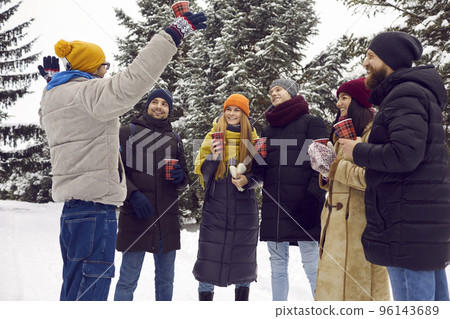 Group of happy young men and women drinking coffee and having fun in winter park 96143689